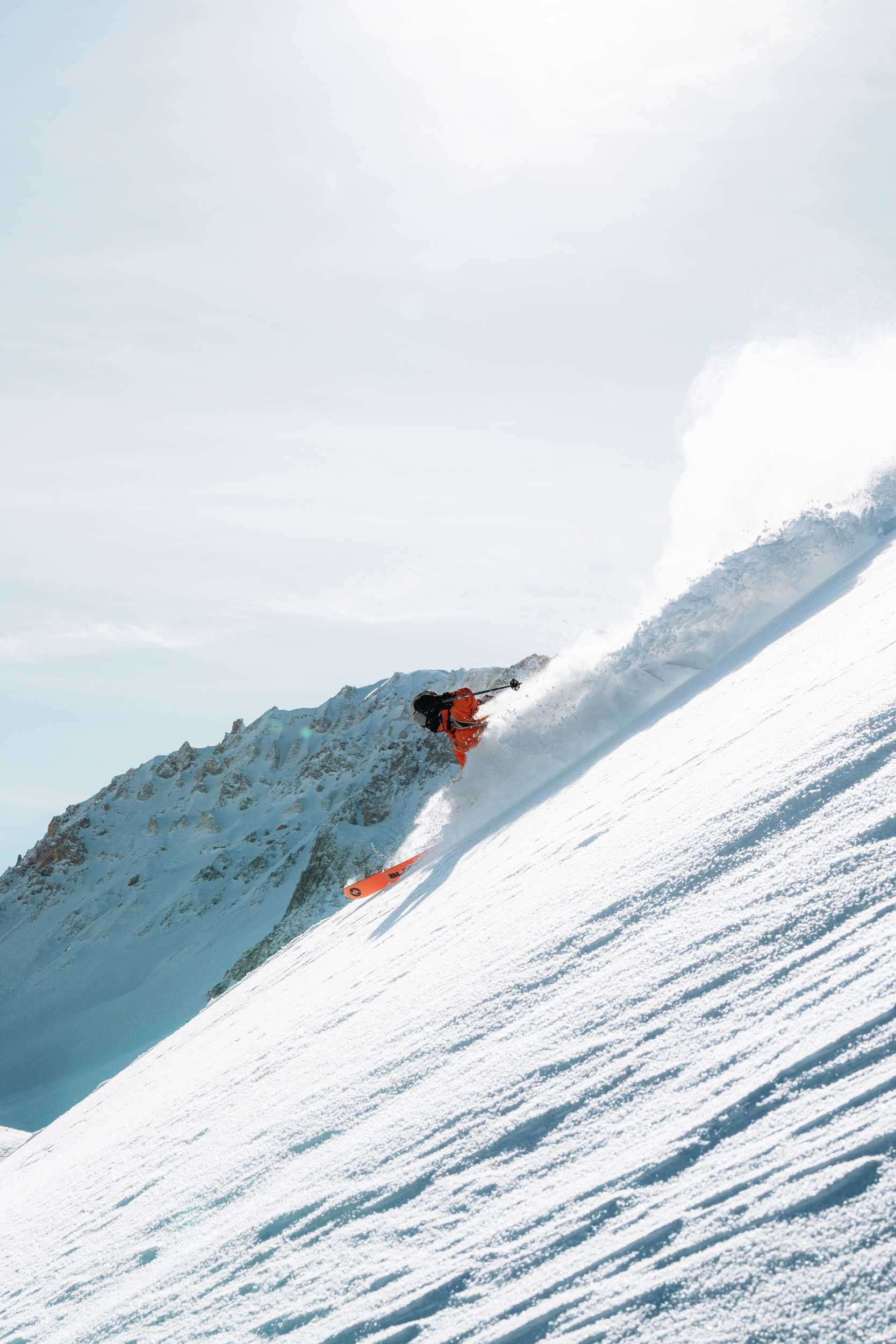 Person skiing down a mountain peak with a view of the summit in the background.